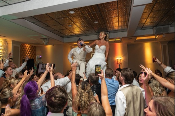 Bride lifted in a chair while the room cheers