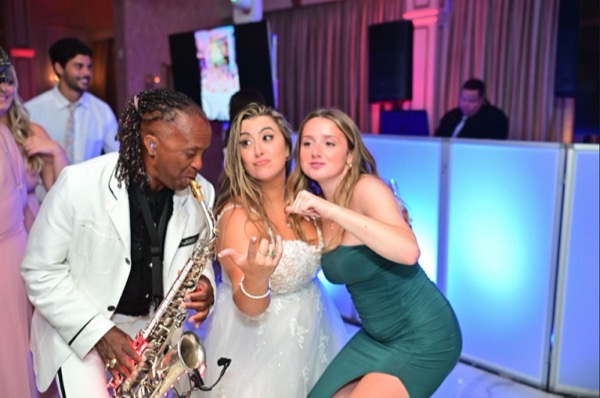 Live sax player in the middle of the crowd with two guests